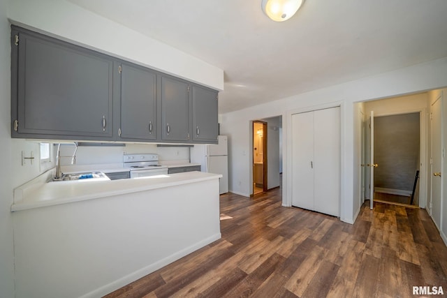 kitchen featuring white appliances, dark wood-style flooring, gray cabinets, light countertops, and a sink