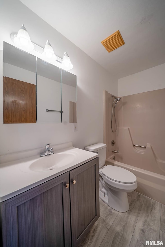 bathroom featuring visible vents, toilet, wood finished floors, vanity, and washtub / shower combination