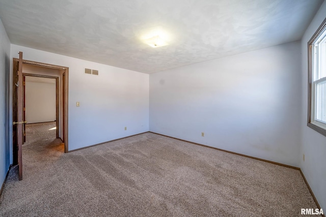 unfurnished room with a textured ceiling, carpet floors, visible vents, and baseboards