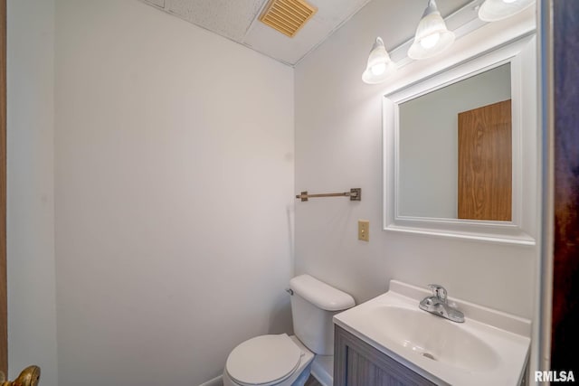 half bathroom featuring visible vents, vanity, and toilet