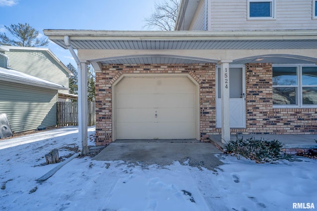 snow covered garage featuring driveway