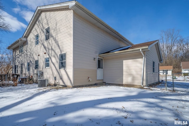 snow covered property featuring cooling unit and fence