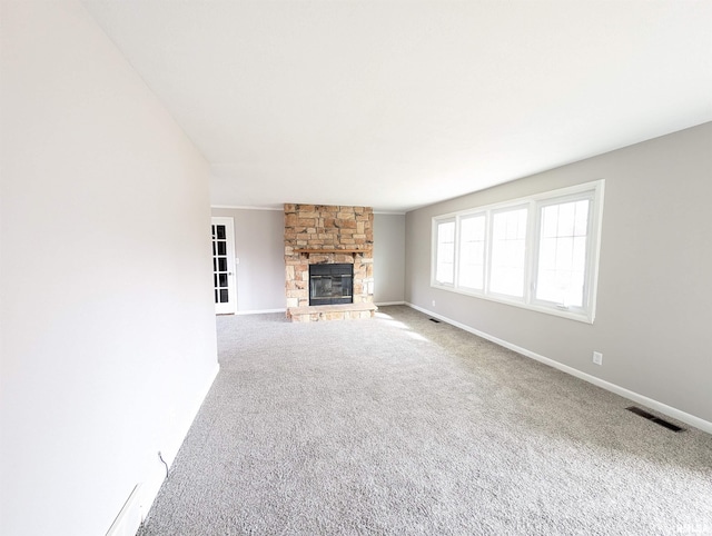 unfurnished living room featuring a stone fireplace and carpet flooring