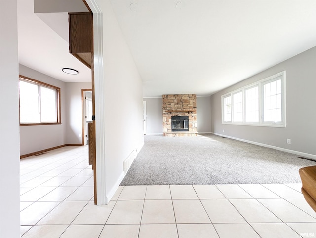 unfurnished living room with a wealth of natural light, light carpet, and a fireplace