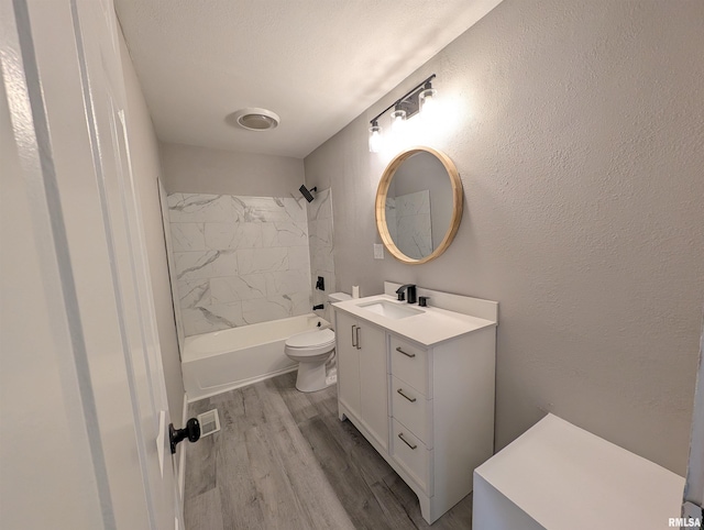 full bathroom featuring hardwood / wood-style floors, toilet, vanity, and tiled shower / bath combo