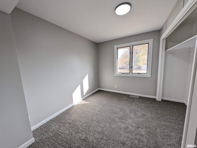 unfurnished bedroom with a closet and dark carpet