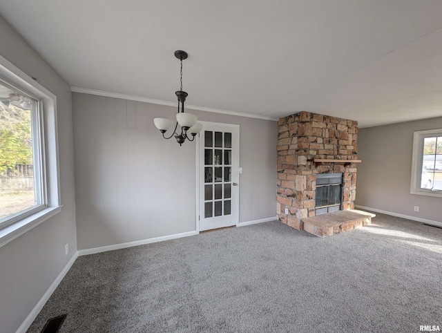 unfurnished living room featuring carpet floors, ornamental molding, a notable chandelier, and a fireplace