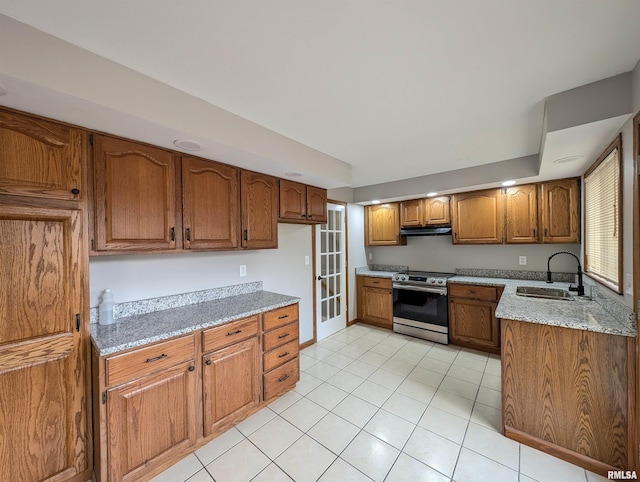 kitchen with stainless steel range with electric stovetop, light tile patterned floors, light stone counters, and sink