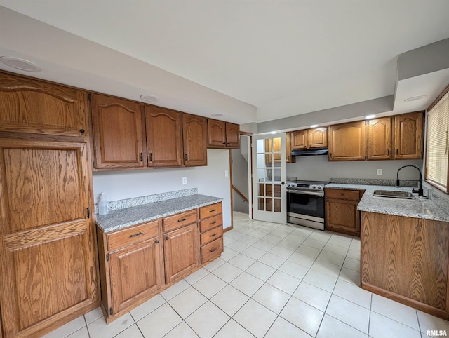 kitchen featuring light stone countertops, electric range, and sink