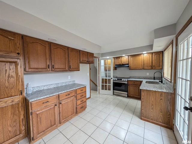 kitchen with light stone counters, sink, light tile patterned floors, and stainless steel range with electric cooktop