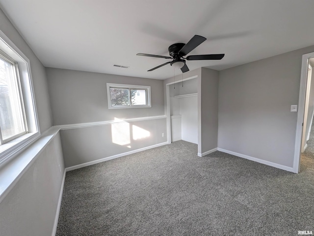 unfurnished bedroom with ceiling fan, multiple windows, and carpet flooring