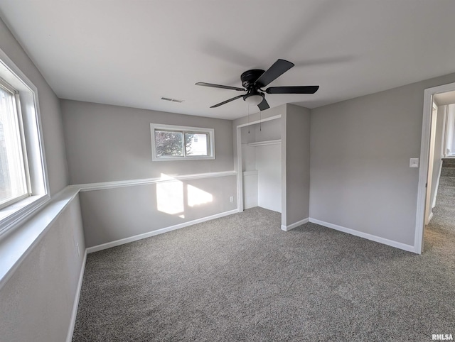 unfurnished bedroom with ceiling fan, a closet, multiple windows, and carpet flooring