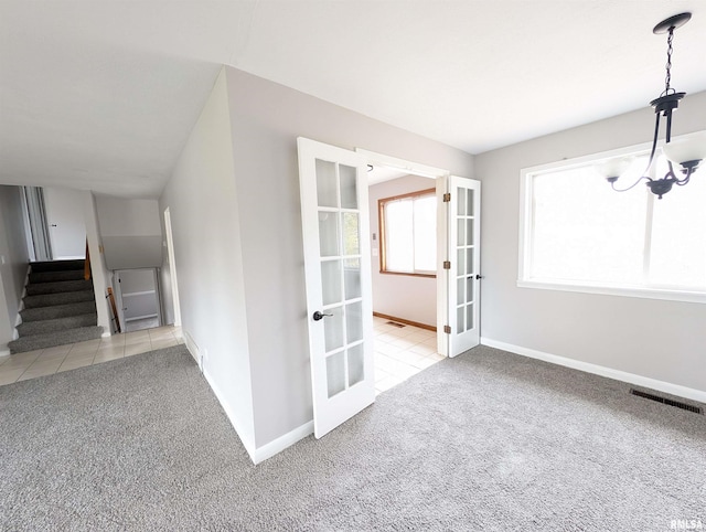 interior space with light colored carpet, french doors, and a notable chandelier