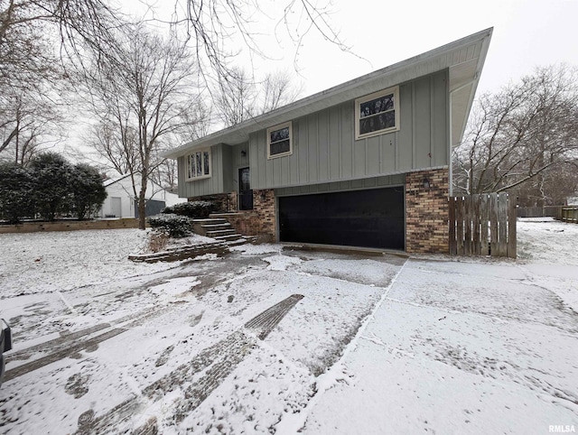 raised ranch with a garage, board and batten siding, and brick siding