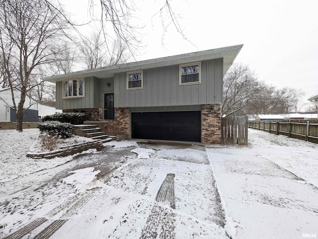 split foyer home with a garage, brick siding, and fence