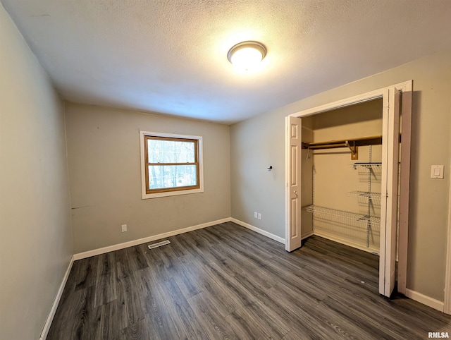 unfurnished bedroom with dark wood-type flooring, a closet, and a textured ceiling