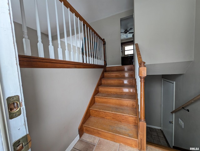 stairway with a ceiling fan and baseboards