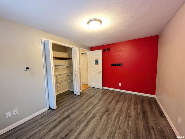 unfurnished bedroom featuring a closet, dark wood-type flooring, and a textured ceiling