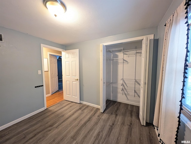 unfurnished bedroom with dark wood-type flooring and a closet