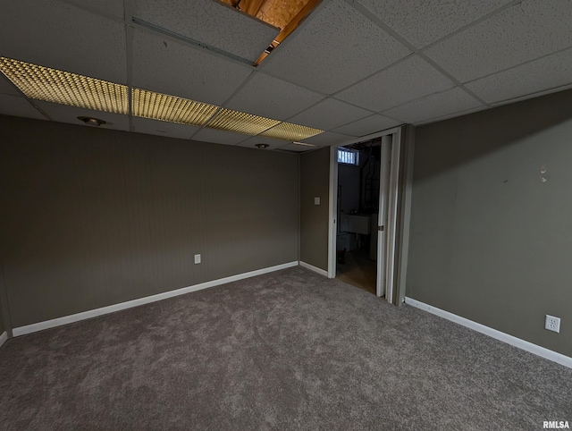 spare room with a drop ceiling and dark carpet