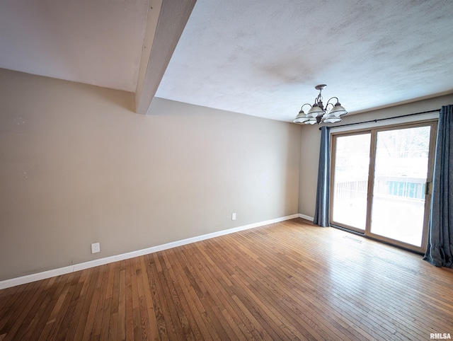 empty room featuring wood-type flooring, beamed ceiling, and an inviting chandelier