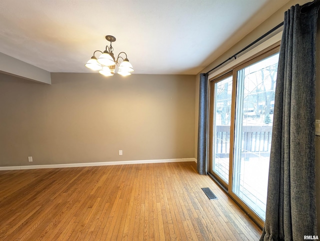 empty room featuring light hardwood / wood-style floors and a notable chandelier