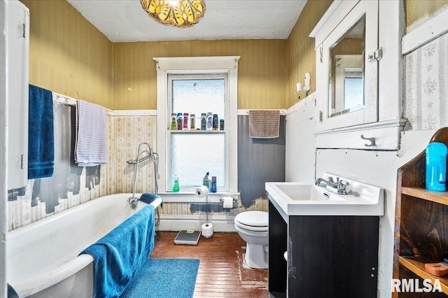 bathroom featuring a bathtub, vanity, wood-type flooring, toilet, and wood walls