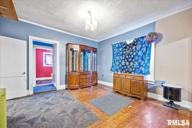 interior space featuring wood-type flooring, a textured ceiling, crown molding, and a notable chandelier