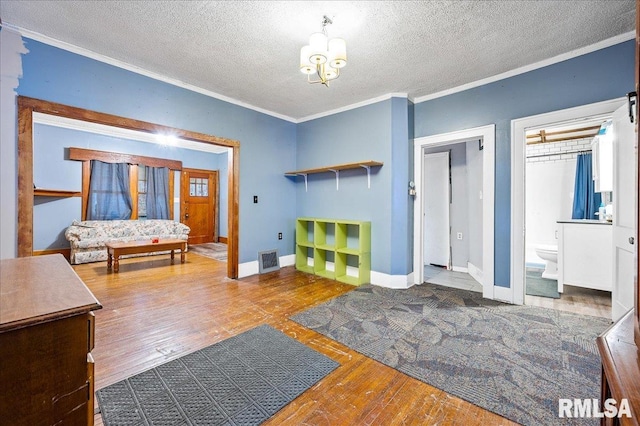 interior space with a notable chandelier, wood-type flooring, a textured ceiling, and ornamental molding