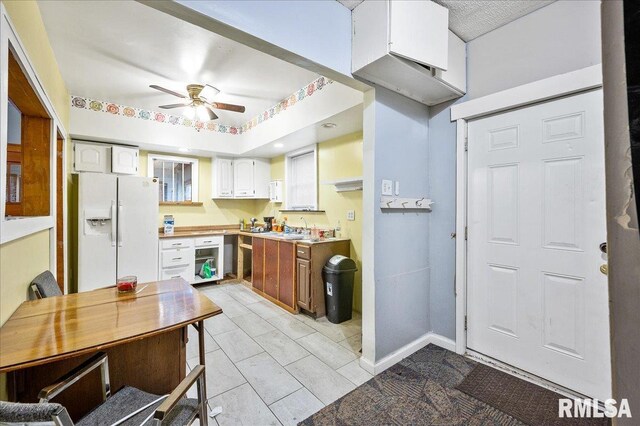 kitchen with ceiling fan, white fridge with ice dispenser, white cabinets, and sink