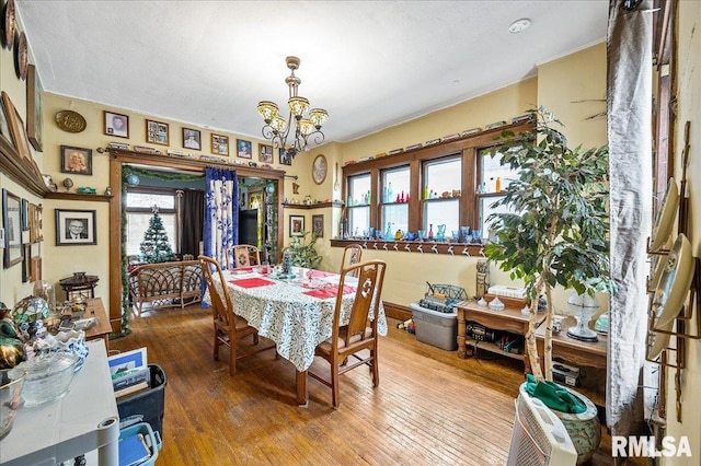 dining room with hardwood / wood-style flooring, a healthy amount of sunlight, and a chandelier