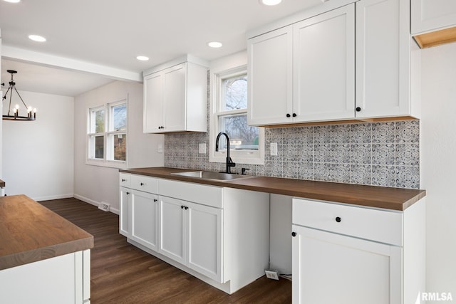 kitchen featuring tasteful backsplash, dark wood-type flooring, sink, white cabinets, and butcher block countertops