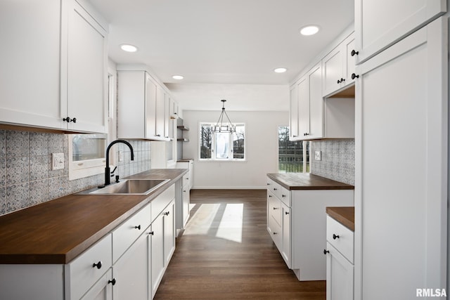 kitchen featuring wood counters, dark hardwood / wood-style flooring, sink, decorative light fixtures, and white cabinets