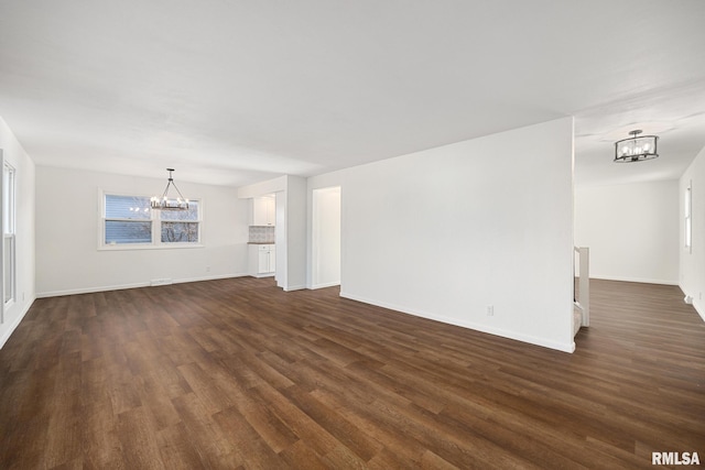 unfurnished living room with dark wood-type flooring and a notable chandelier