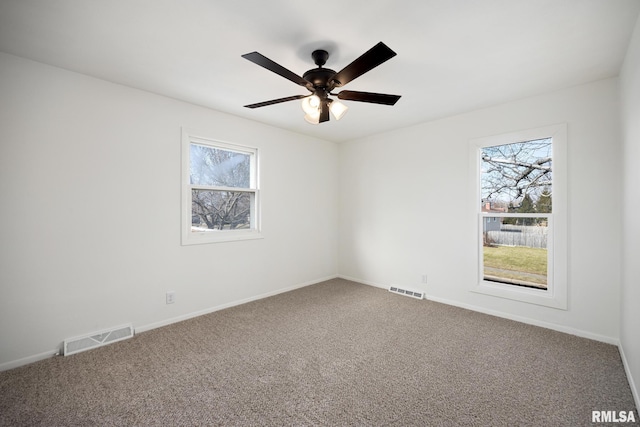 carpeted spare room featuring ceiling fan and a wealth of natural light