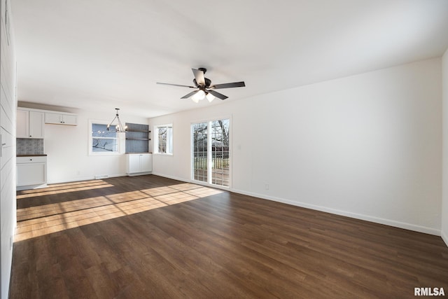 unfurnished living room with dark hardwood / wood-style floors and ceiling fan with notable chandelier