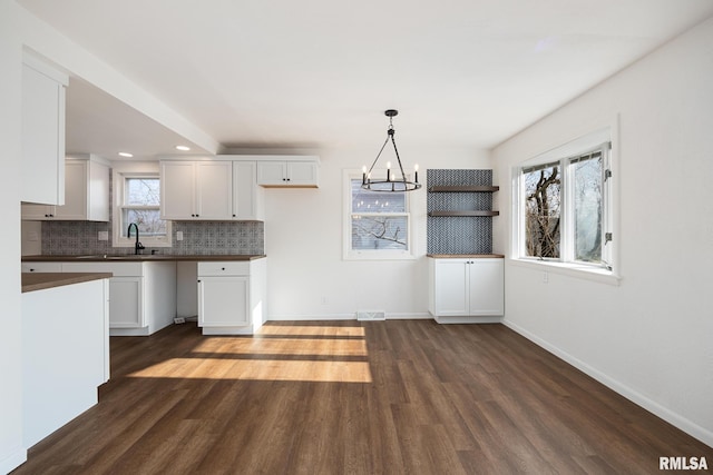 kitchen featuring pendant lighting, white cabinetry, dark wood-type flooring, and sink