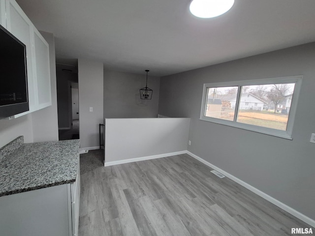 unfurnished dining area with light wood-style floors, visible vents, and baseboards