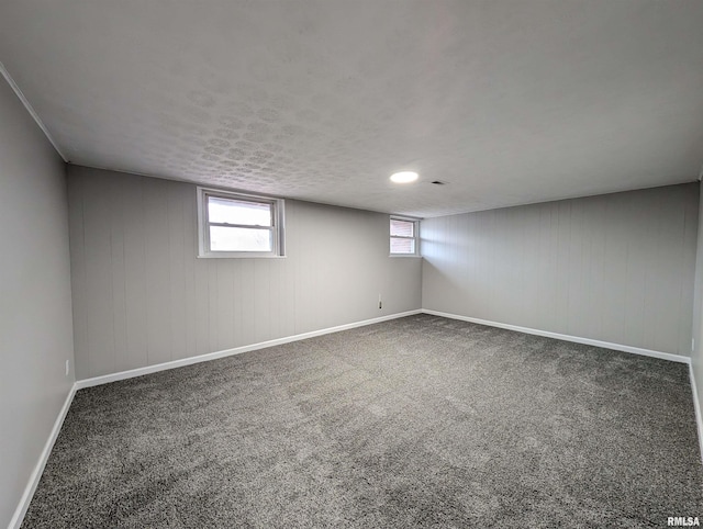 below grade area with a textured ceiling, carpet floors, and baseboards