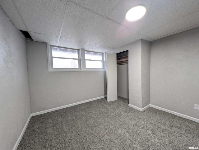 below grade area with a textured wall, carpet, a paneled ceiling, and baseboards