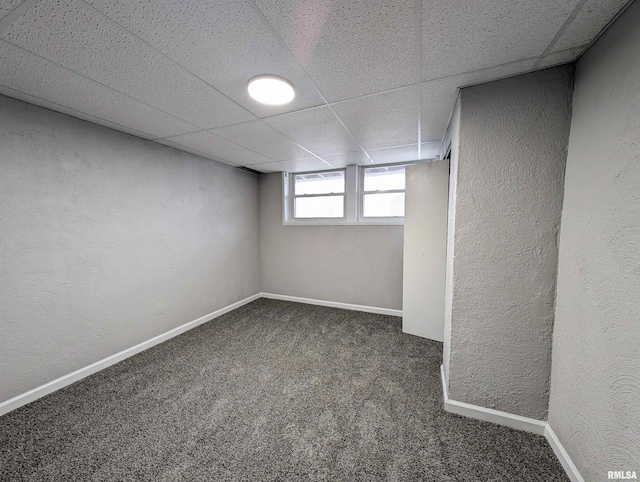 below grade area featuring a textured wall, a drop ceiling, carpet flooring, and baseboards