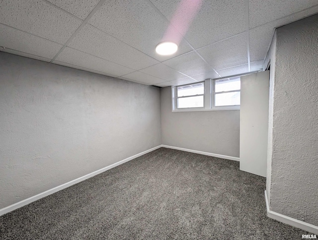 below grade area with a textured wall, carpet floors, a paneled ceiling, and baseboards