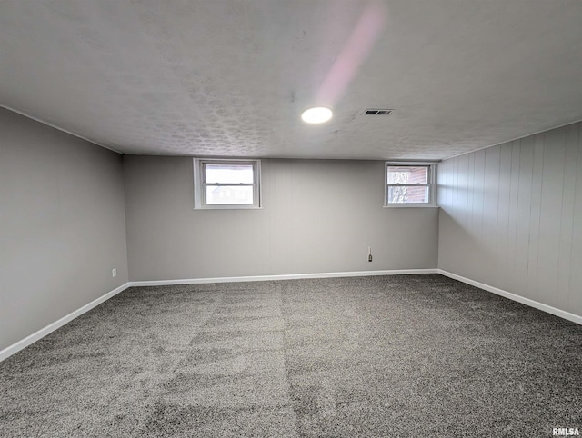 basement featuring a healthy amount of sunlight, baseboards, visible vents, and carpet flooring