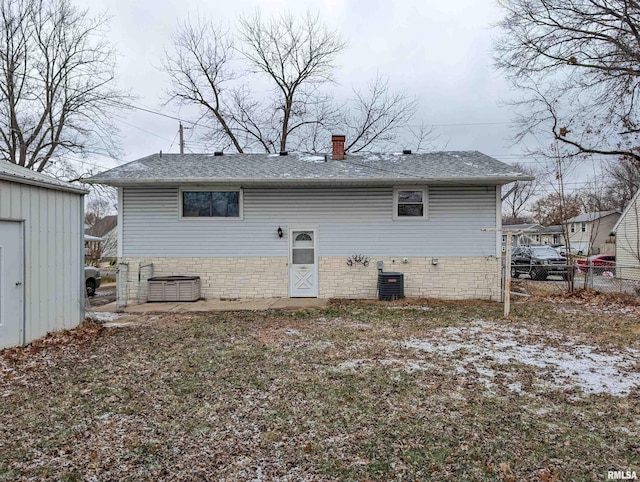 rear view of property featuring a chimney, a shingled roof, crawl space, central AC, and fence