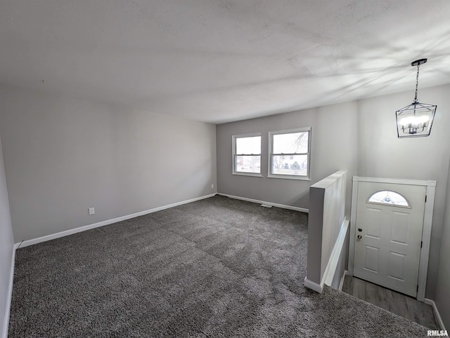 foyer featuring carpet, baseboards, and a chandelier