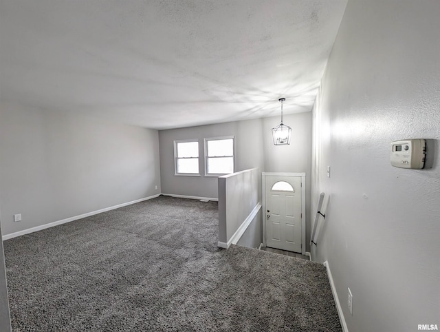 foyer entrance featuring carpet, baseboards, and an inviting chandelier