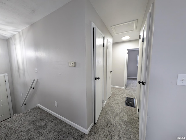 hallway with attic access, baseboards, visible vents, carpet flooring, and an upstairs landing