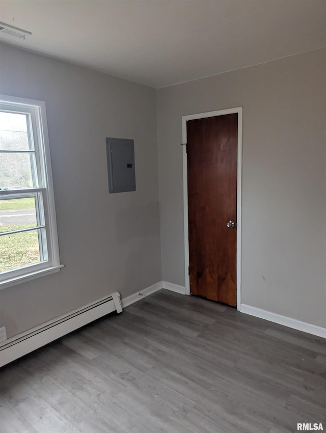 unfurnished room featuring a baseboard heating unit, light hardwood / wood-style flooring, and electric panel