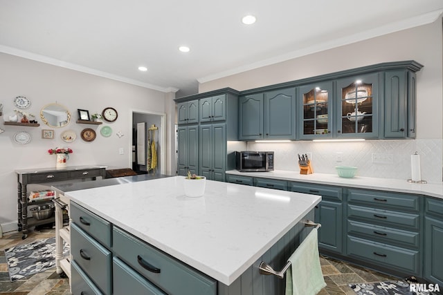 kitchen with decorative backsplash, blue cabinets, a kitchen island, and ornamental molding