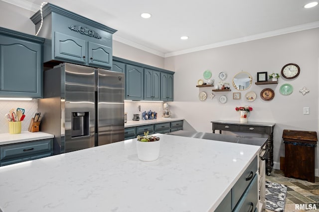 kitchen with light stone countertops, stainless steel refrigerator with ice dispenser, tasteful backsplash, ornamental molding, and blue cabinetry